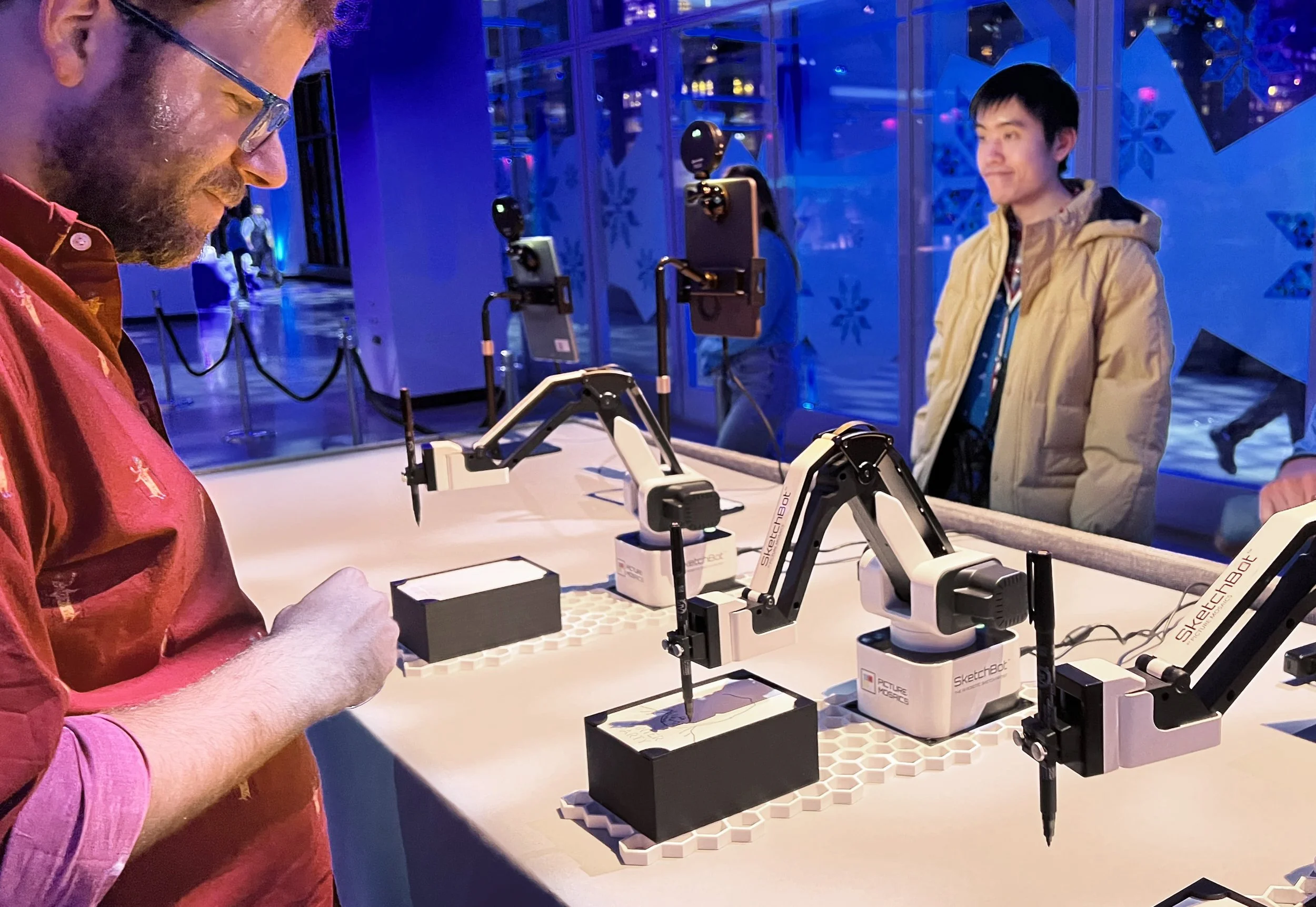 Robotic arms drawing portraits while guests watch