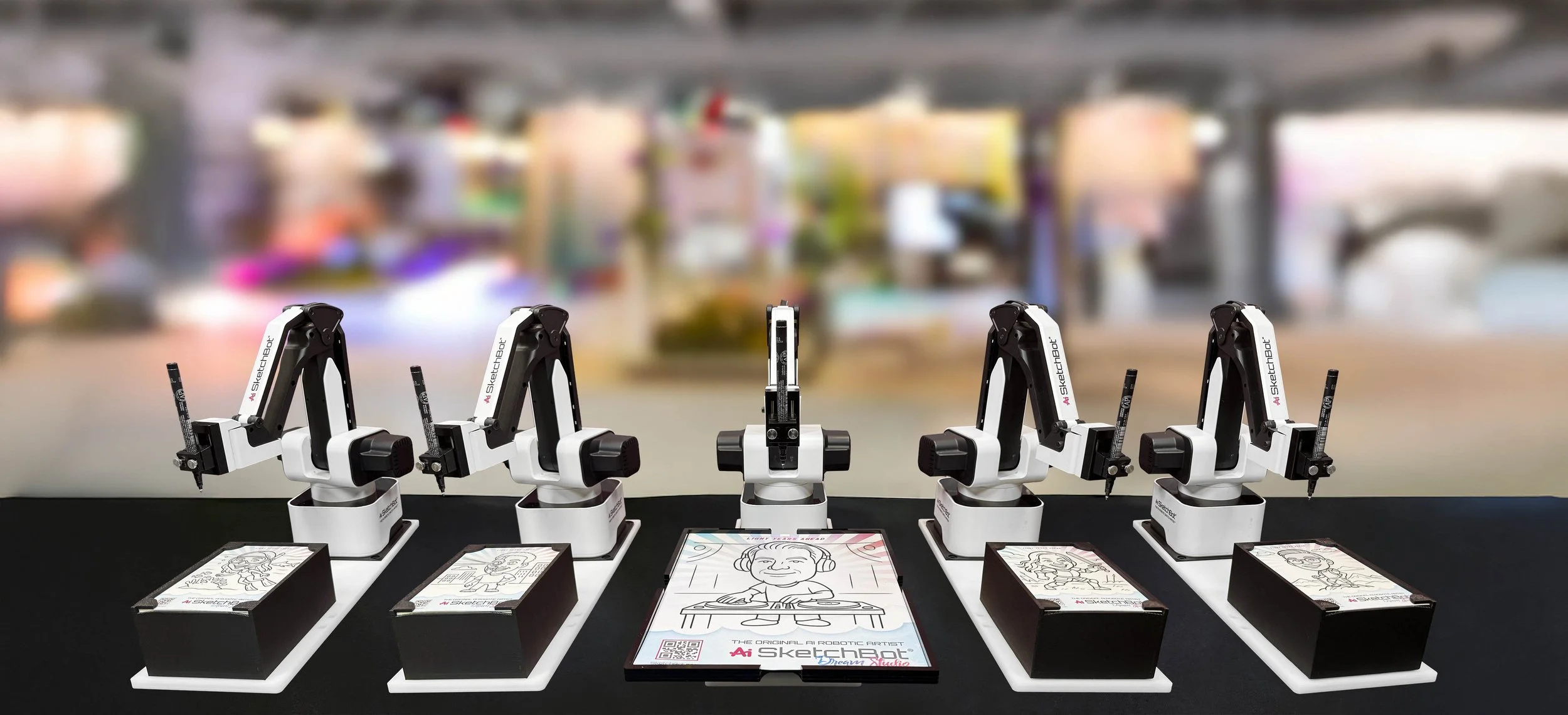 Five robotic drawing stations displaying finished portrait sketches